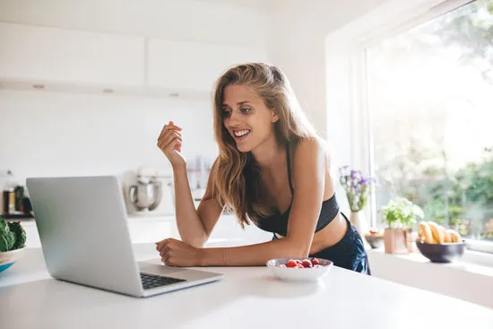 Beautiful young woman in kitchen with laptop